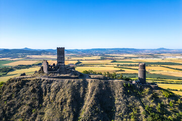 Hazmburk castle ruins rise dramatically atop a hill in Czechia, surrounded by the scenic Central Bohemian Uplands. The historical site offers breathtaking views of the lush, expansive landscape below.