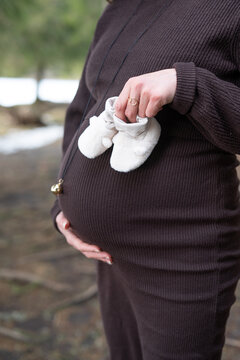 Femme enceinte tenant des petits chaussons de b&eacute;b&eacute; devant son ventre