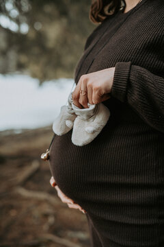 Femme enceinte tenant des petits chaussons de b&eacute;b&eacute; devant son ventre