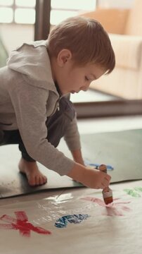 Young child painting on floor with colorful tempera