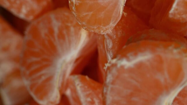 A conceptual 4K timelapse loop that begins with a whole mandarin rotating on a plate, then seamlessly deconstructs into its orbiting segments, which further dissolve into a pulsating, kaleidoscopic