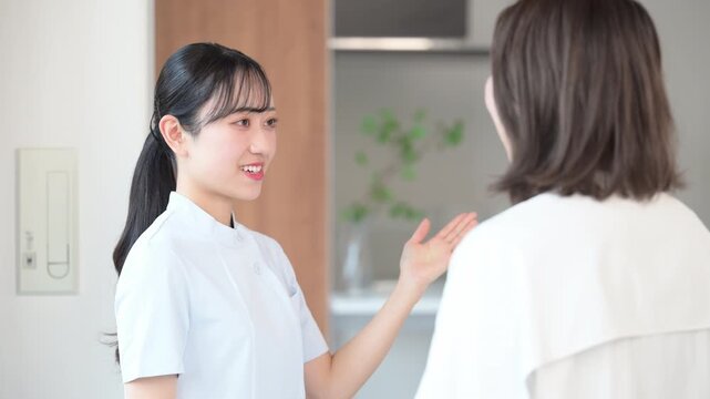 看護師などの医療従事者が患者に向けて丁寧に説明し案内するクリニックの受付などのシーン　こちらです 患者の顔無しの動画