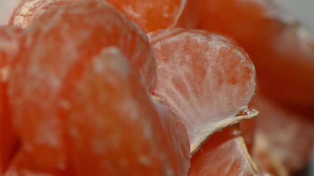 A captivating, abstract 4K motion loop where succulent mandarin segments swirl in a vortex-like formation on a dark surface, creating a dynamic kaleidoscope of orange, white, and translucent textures