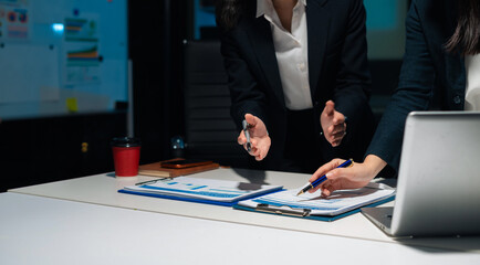 Financial analysts work overtime analyzing data on tablets, laptops, and graphs.