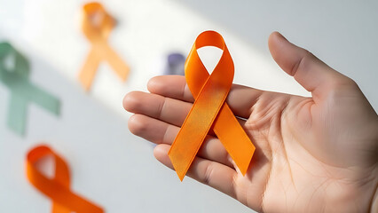 Hand holding orange awareness ribbon for cancer support and health campaign