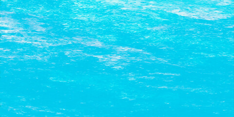 A clean blue water surface features clear turquoise ripples and liquid textures, creating a cool abstract background of swimming pool waves and transparent summer ocean reflections