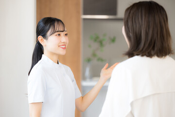 看護師などの医療従事者が患者に向けて丁寧に説明し案内するクリニックの受付などのシーン　こちらです 患者の顔無し