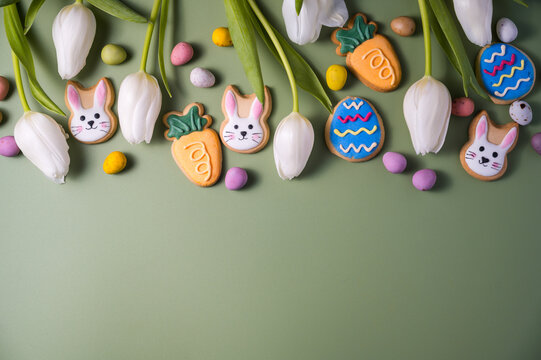 Easter spring holiday background with easter cookies: buny, carrot and egg with white tulip flowers, flat lay