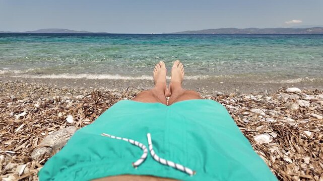 Man sunbathing on a rocky sea ocean beach.