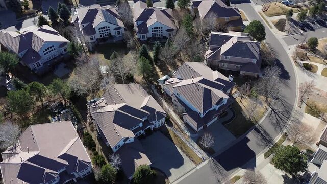 Beige and gray rooftops near South Zeno Way form a grid-like pattern along landscaped curve. Suburban home with solar panels, leafless trees and soft shadows winter scene, Aurora, Colorado
