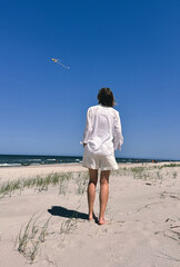 woman walking on the beach with kit on the wind 