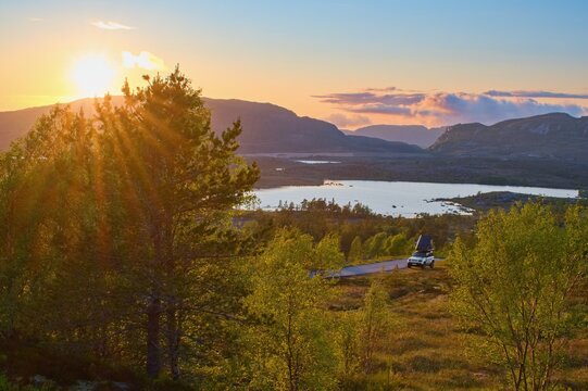 Off road car with roof tent in the wild campground within sunset. Norway road trip.