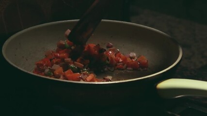 Sauteing chopped vegetables and ham cubes in a pan to make fried rice, candid authentic domestic moment of daily life at home