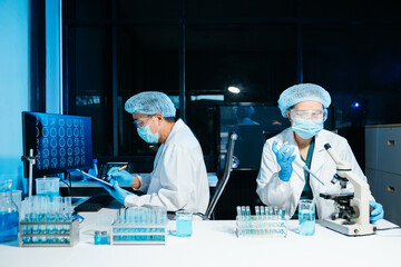 Medical scientists working in laboratory using microscope and analyzing brain scan data for diagnostics and research, reflecting healthcare technology and professional laboratory environment.