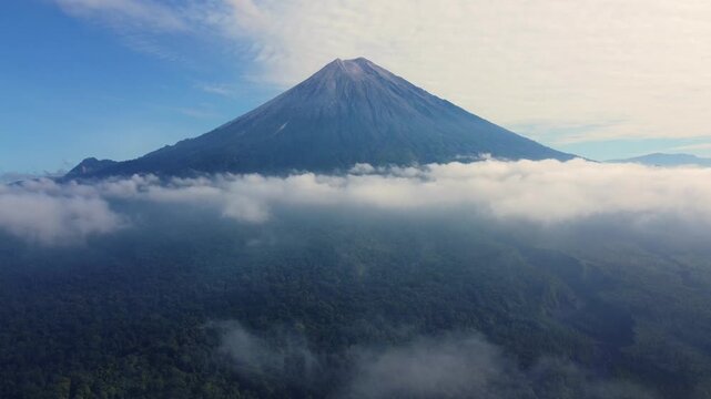 Stone river, stone deposit and Mount Semeru. Volcano clouds of smoke against the blue sky. Active volcano on the island of Java in Indonesia. Ash pillar from a bird's eye view. Dron. 4K