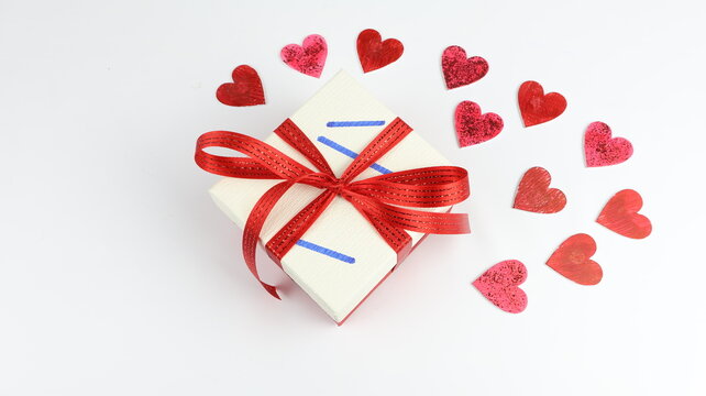 Una scatola regalo con un fiocco rosso e tanti cuori rossi su sfondo bianco. Un'ottima idea per feste e San Valentino.
