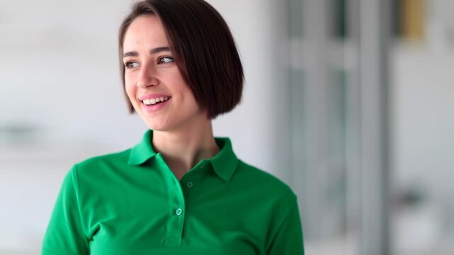 A smiling woman with short brown hair is wearing a green polo shirt and looking to the left
