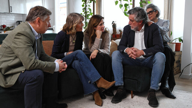 Mature friends dialoguing, supporting each other in living room