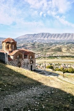 View of the medieval Byzantine Holy Trinity Church located on a hillside within the Berat Castle complex, overlooking the city of Berat, the Osum River valley, and the surrounding mountains in Albania