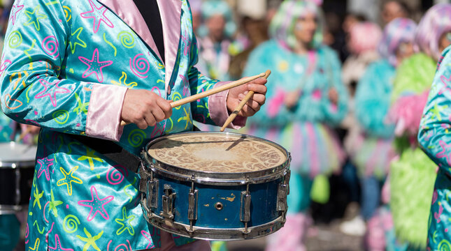 Carnival drummer playing snare drum in colorful costume during street parade.