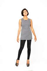 Fototapeta premium Energetic confident young Indian woman posing in a black-and-white striped sleeveless top, black jeans, high heels against white background, ideal for fashion, beauty, self confidence, minimal style.