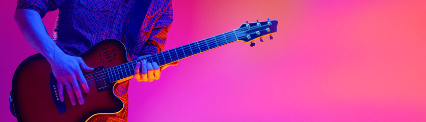 Electric guitar player hands performing on colorful studio background. Concept of live music...