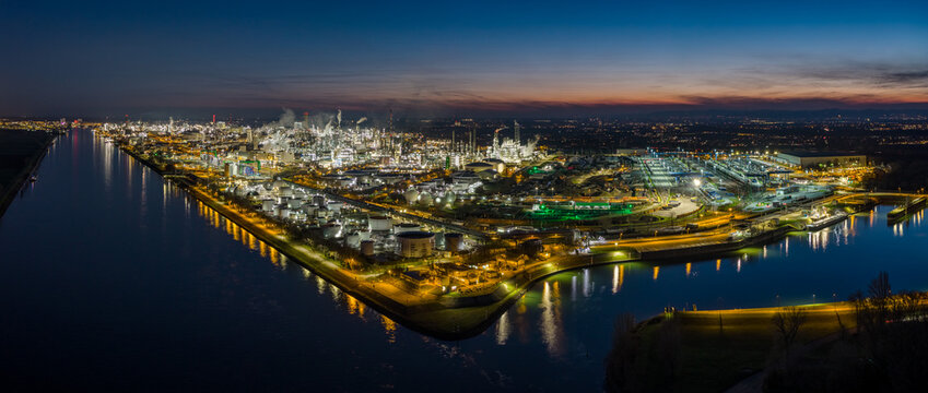 Aerial view of the BASF industrial complex illuminated against the twilight sky, nestled between dark waterways, Ludwigshafen am Rhein, Rheinland-Pfalz, Germany.