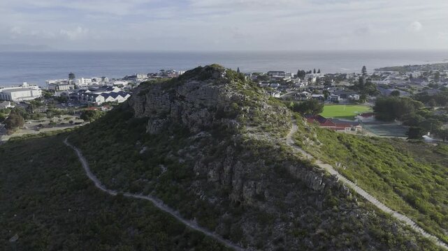 Drone flies from medium shot south over Hoy's Koppie in the late afternoon along the Garden Route on a sunny day in Hermanus, South Africa