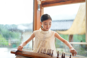 A young girl is playing a traditional Chinese instrument. Concept of cultural appreciation and the importance of preserving traditional art forms
