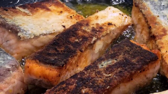 Healthy omega-3 rich salmon fish fillets being pan-fried for a nutritious dinner