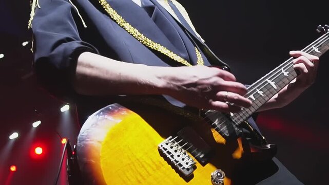 Guitarist in stylish jacket plays music against red lights in night club closeup. Musician performs electric instrument composition on stage