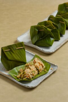 Bothok or bothok on brown background. Bothok is traditional Indonesian food. Made from tempeh, anchovy, chinese map and coconut grater wrap with banana leaf. Javanese food