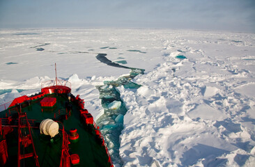 Red research vessel breaking through Arctic sea ice in Greenland polar waters