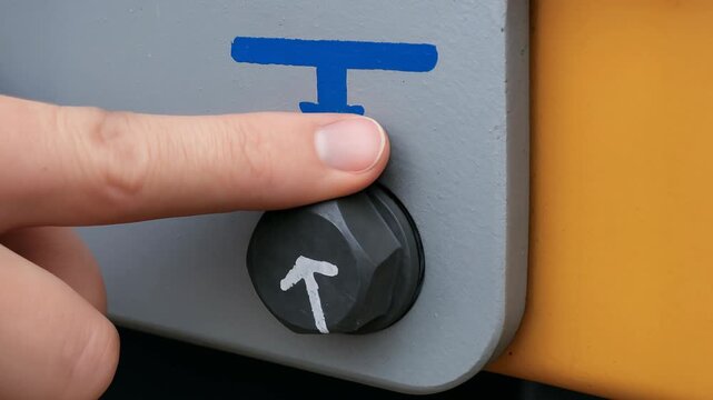 Finger presses button arrow symbol control safety crane panel bolt metal surface touch direction indicator industrial instruction closeup