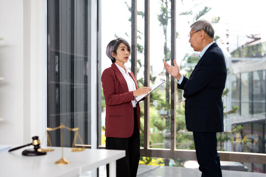 Lawyer, solicitor or barrister, supervisor talk to analyse case report, discussing paper policy terms conditions with client, conduct lawsuits document