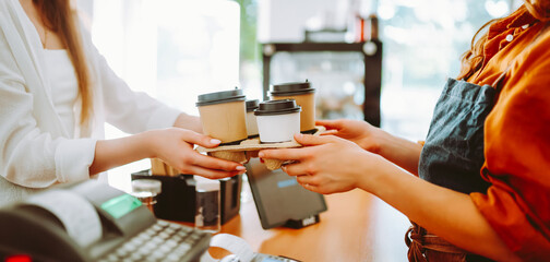 A portrait of a young woman stands in a coffee shop with a digital tablet at the bar on a sunny day. A female barista works in a cozy coffee shop. Small business concept, beverages, and technology.