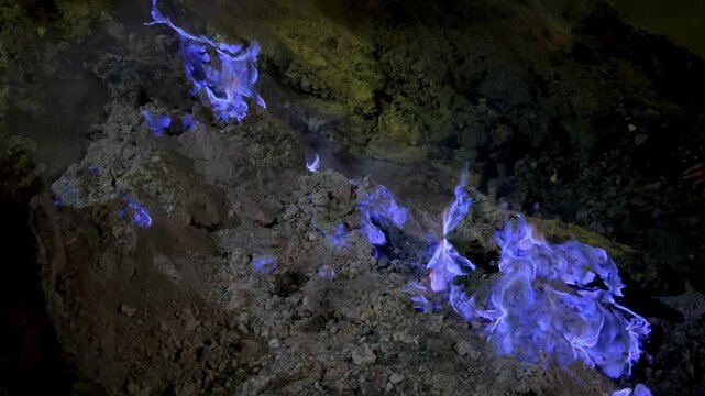 The blue flame of Kava-Ijen volcano burns on the dark earth, creating a stunning display of sulfuric gases at night. Java, Indonesia. Close-up of the famous blue flame phenomenon in the crater of Ijen