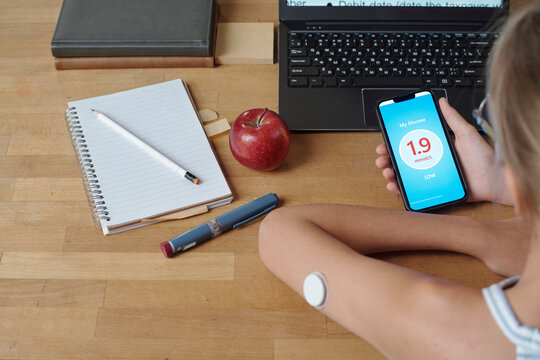 Person checking glucose level with mobile app and insulin patch