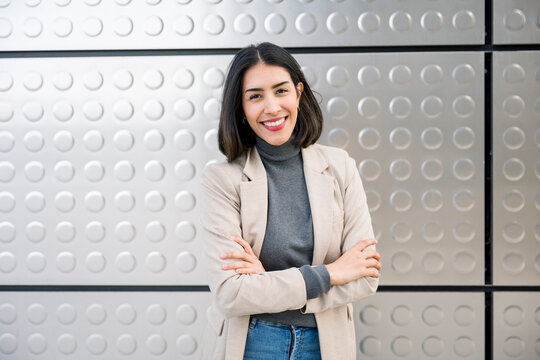 Confident businesswoman entrepreneur standing with crossed arms indoors