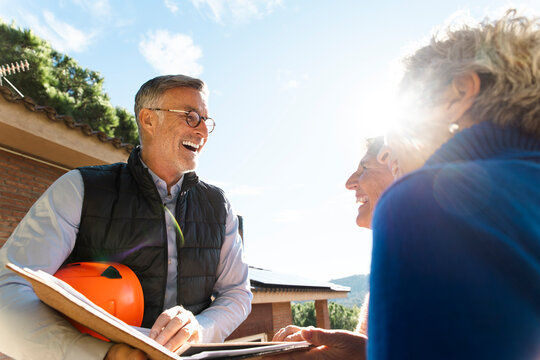 Engineer and homeowners consulting on solar panel installation outdoors