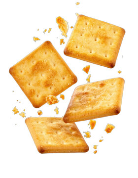 Four golden square crackers suspended mid-air against a black background with crumbs scattered around.