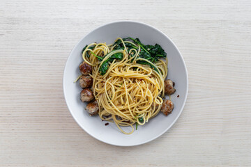 A plate of spaghetti with sausage and spinach.