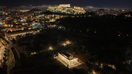 Naklejka premium Aerial drone night shot of amazing illuminated ancient market of Athens or Agora featuring temple of Hephaestus, picturesque Plaka district and Acropolis hill, Attica, Greece