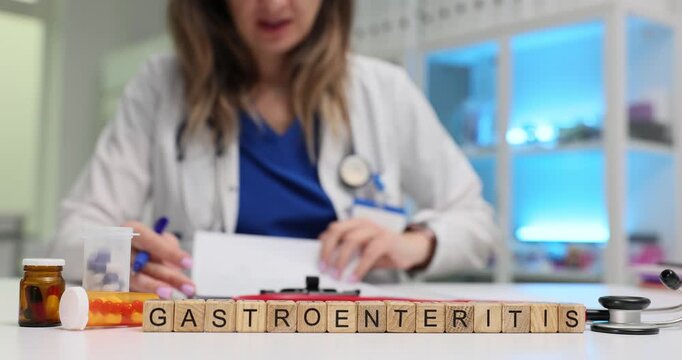 Wooden cubes spell word Gastroenteritis near pills and stool sample cup. Woman doctor holds documents recording symptom history for stomach infection