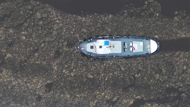 Top down aerial video of icebreaker tugboat at aqueduct in winter