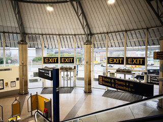 Naklejka premium Busy transport Manchester airport hub interior with large exit signs and directional signage for trains and buses