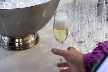 Close-up of a champagne flute filled with golden bubbly drink, placed beside a large metallic ice...