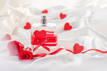 Festive BACKGROUND  for valentine's day  with A bottle of perfume with hearts, a bow and  RED roses. Promotional offer for perfume
