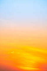 Obraz premium Sunset or sunrise sky with a vibrant gradient of orange, gold, and soft blue. Clear atmosphere with wispy clouds. Peaceful, natural light background. hope, freedom, new day Concepts, Vertical