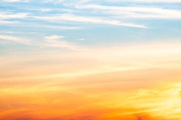 Obraz premium Sunset or sunrise sky with a vibrant gradient of orange, gold, and soft blue. Clear atmosphere with wispy clouds. Peaceful, natural light background. hope, freedom, new day and inspirational Concepts